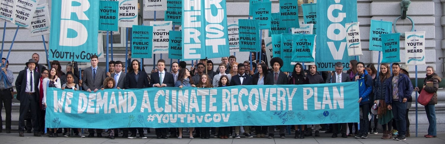 Our Children's Trust members holding a banner "We Demand A Climate Recovery Plan"